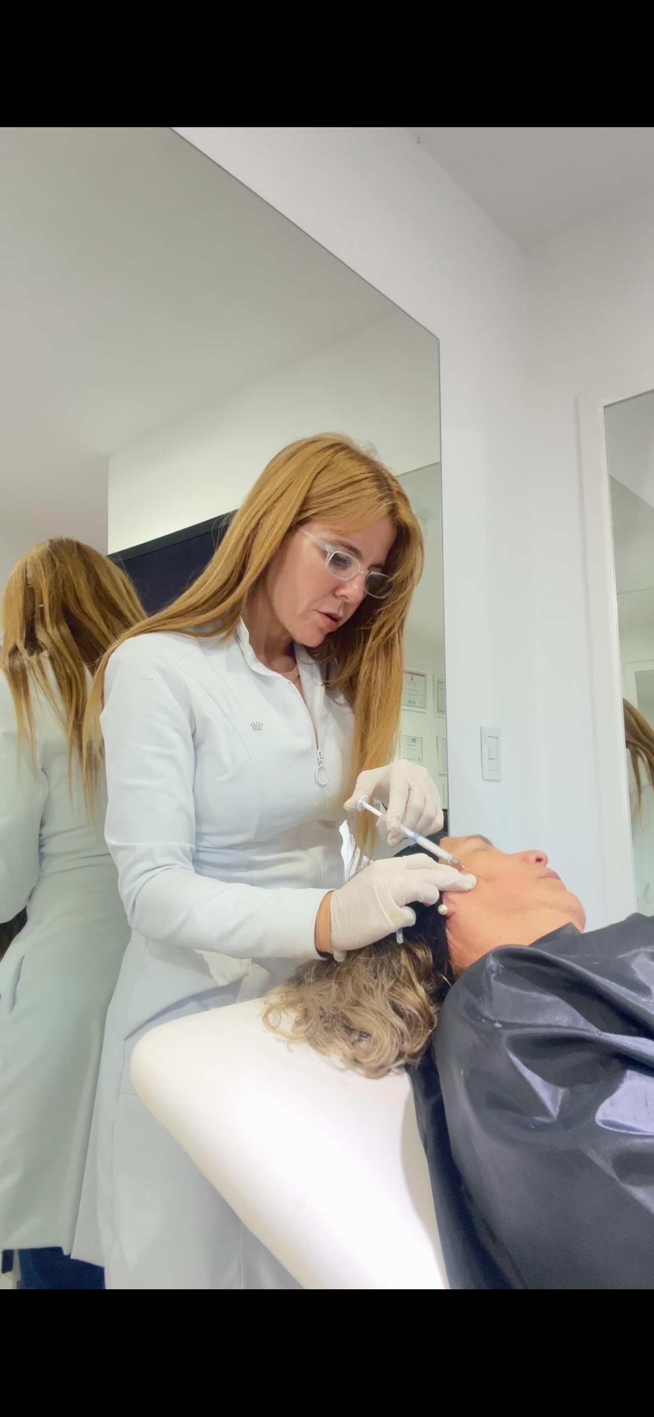 Dra. Peláez aplicando tratamiento en consultorio, frente al espejo